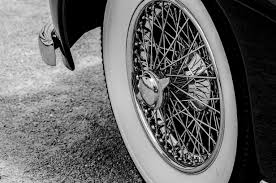 Close-up of a classic car wheel with wire spokes and whitewall tire