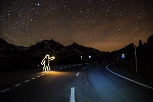 A glowing human shape sign board on a highway at night time