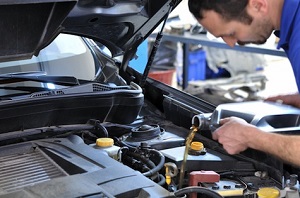 A man pours oil into a car engine