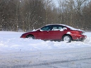 A red car is trapped in a thick layer of snow