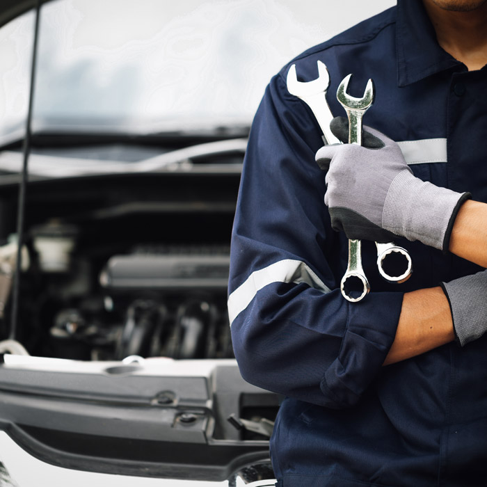 mechanic holding tools in front of car