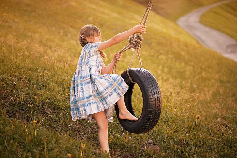 Child playing on tire swing outdoors