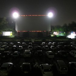 Drive-in theater at night with cars parked facing a large screen