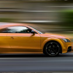 Bright orange sports car speeding on road with motion blur background