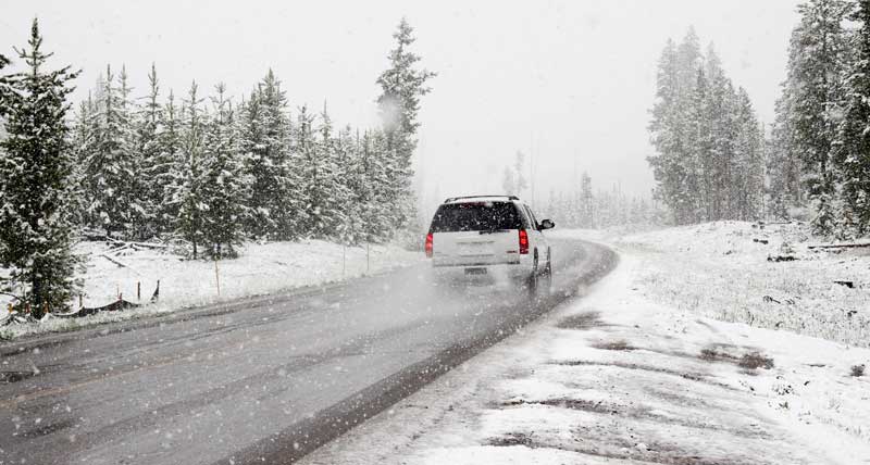 SUV driving on snowy road during snowfall